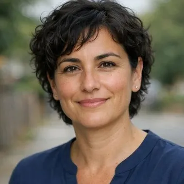 Woman in early forties, short dark curly hair, olive skin, calm expression